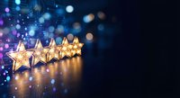 Five golden stars with warm lighting against dark blue bokeh background for rating, review, excellence and quality concepts in business presentations.