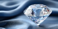 Brilliant cut diamond with prismatic light reflections on flowing silk fabric background showcasing luxury jewelry and precious gemstone elegance.