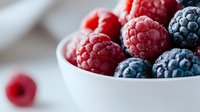 Fresh mixed berries in white bowl with raspberries and blueberries for healthy breakfast, dessert or smoothie ingredients on kitchen counter.
