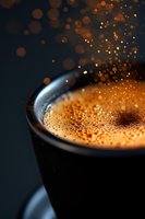 Steaming hot coffee cup with golden foam and sparkling bokeh lights creating warm atmospheric mood for cafe and beverage concepts.