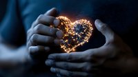 Glowing heart-shaped fairy lights held gently in female hands against dark background, creating magical romantic atmosphere for Valentine's day or wedding decor.