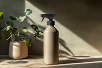 Minimalist beige spray bottle with eucalyptus plant in ceramic pot on neutral background with dramatic sunlight and shadows creating modern composition.