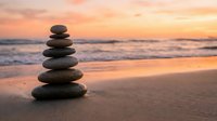 Balanced stone cairn on sandy beach at sunset with ocean waves and colorful sky creating peaceful meditation scene for wellness and mindfulness concepts.