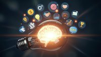 Glowing light bulb with brain inside surrounded by floating business icons representing innovation, creativity and entrepreneurship on dark background.