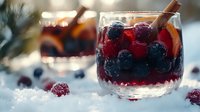 Festive winter cocktail with mixed berries and cinnamon stick in glass mug, warm holiday drink with cranberries and blackberries on snowy surface.
