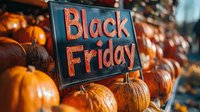 Orange pumpkins surrounding chalkboard sign with Black Friday text in rustic autumn setting, creating seasonal shopping atmosphere with warm lighting effects.
