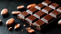 Dark chocolate bar with cocoa beans scattered on black stone background, macro food photography showing texture and details for culinary and confectionery designs.