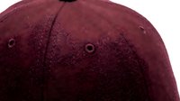 Close-up of a burgundy wool baseball cap showing fabric texture, stitching details, and ventilation eyelets for fashion and apparel design use.