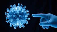 Blue gloved hand pointing at glowing coronavirus particle on dark background for medical education and pandemic awareness concepts.