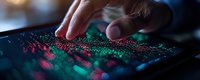 Fingers touching digital screen with vibrant pink and green particle visualization display, showing interactive data analytics and modern technology interface.