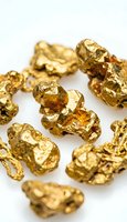 Raw gold nuggets scattered on white background showing natural metallic texture and irregular shapes for mining and precious metals concepts.