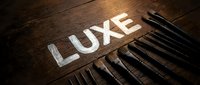 Luxury makeup brushes arranged next to chalk lettering on dark wooden surface, representing cosmetics, beauty tools, and professional makeup application.