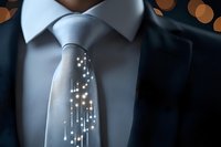 Glowing digital lights illuminate gray necktie against white collar and dark suit, creating futuristic business concept with bokeh background effect.
