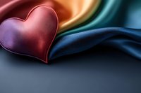 Red metallic heart on flowing silk fabric in vibrant rainbow colors against dark background creates romantic mood for Valentine's Day designs and love themes.