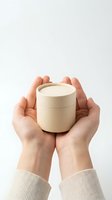 Hands gently holding small round cardboard container with lid, eco-friendly packaging concept for sustainable products and zero waste lifestyle.