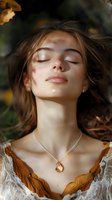 Young woman with long brown hair and fair complexion, eyes closed in peaceful expression, wearing delicate pendant necklace and earth-toned garment, surrounded by autumn foliage and natural lighting for wellness and lifestyle use.