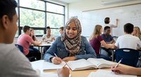 Young Muslim woman in hijab studying in modern classroom with diverse students working at desks during educational session.