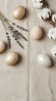 Natural Easter eggs in beige tones with dried lavender and cotton flowers on linen fabric background for spring holiday decoration and organic crafting projects.