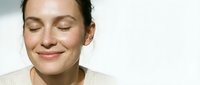 Young Caucasian woman with closed eyes and gentle smile showing natural skincare routine results on clean white background for beauty campaigns.