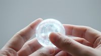 Hands holding transparent sphere with digital holographic interface and data visualization for technology, innovation, and future business concepts.