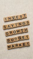 Wooden letter blocks spelling financial terms invest savings growth budget market on neutral linen texture background for business planning concepts.