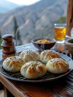 Traditional Middle Eastern pastries with herbs on rustic plate served with tea against mountain landscape backdrop for authentic cultural dining experience.
