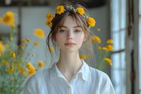 Young Caucasian woman with natural makeup wearing white shirt and yellow flower crown, soft dreamy portrait near window with yellow flowers in foreground creating romantic mood.