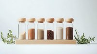 Glass spice jars with wooden lids arranged on wooden stand containing various cooking ingredients, seasonings and coffee beans, decorated with fresh herbs.