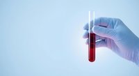 Medical professional in blue latex gloves holding test tube with red blood sample for laboratory analysis and diagnostic testing procedures.