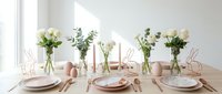 Elegant dining table setting with fresh flowers in glass vases, pink ceramic dishes and copper wire decorations for special occasions and celebrations.