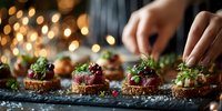 Elegant appetizers with tuna tartare on crispy bread rounds, garnished with fresh herbs and microgreens, served at festive gathering with bokeh lights.