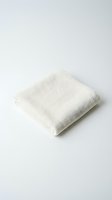 Folded natural linen towel on white background, showcasing organic cotton texture, eco-friendly fabric for home, spa, and wellness product photography.