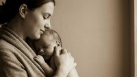Tender moment of young mother holding sleeping newborn baby in warm embrace. Maternal love and bonding concept for parenting and family themes.