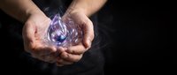 Male hands holding glowing purple crystal or gemstone with magical energy against dark background. Mystical concept for spirituality, healing, power.
