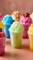 Colorful shaved ice cups with vibrant fruit flavors including blue, pink, yellow, and green varieties topped with fresh berries on neutral background for summer beverage marketing.