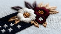 Embroidered floral design with white and burgundy flowers on dark fabric. Detailed needlework featuring decorative stitching and botanical motifs for craft projects.