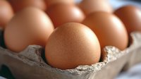 Fresh brown chicken eggs in cardboard carton, selective focus on single egg in foreground, natural food photography for healthy cooking and baking concepts.