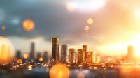Stacks of golden coins against blurred cityscape background with warm sunset light and bokeh effects creating wealth and financial success concept.