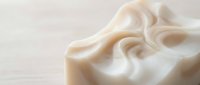 Luxurious cream silk fabric with elegant flowing folds and soft draping texture on neutral background for fashion and textile design projects.