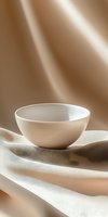 Minimalist white ceramic bowl positioned on draped beige fabric with soft natural lighting and warm shadows, suitable for product photography, home decor, tableware design, and lifestyle marketing materials.