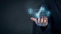 Business professional holding glowing digital network icons with security lock symbols representing cybersecurity and data protection technology solutions.