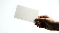 Hand holding blank white textured card against clean background for mockup design templates and branding presentations.