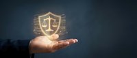 Businessman hand holding glowing digital shield with scales of justice symbol representing legal protection and cybersecurity concepts for business.