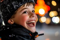 Joyful young Caucasian boy wearing winter hat laughing outdoors at night with colorful bokeh lights and warm glowing atmosphere in background. Perfect for holiday themes.