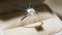 Sparkling diamond solitaire engagement ring in a velvet box, with brilliant light rays reflecting off the gemstone, symbolizing love and luxury.