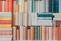 Rows of vintage hardcover books arranged on shelf in pastel coral, mint, and neutral colors creating minimalist aesthetic pattern for home library decor.