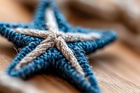 Handcrafted blue and beige knitted starfish decoration on wooden surface, close-up view with soft focus background for coastal home decor.