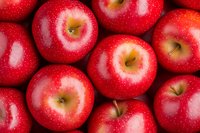 Fresh red apples with water drops background. Ripe organic fruits arranged in rows showing glossy skin and natural texture. Macro food photography.