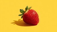 Fresh ripe strawberry with green leaves on bright yellow background casting shadow. Healthy organic fruit for summer recipes and nutrition concepts.