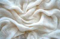 Soft white linen fabric with gentle folds and natural texture creates flowing waves and shadows, suitable for fashion, wedding, or interior design backgrounds.